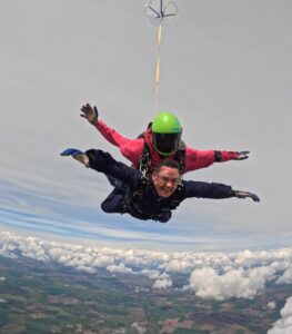 Craig Symonds mid-skydive during a charity jump for the Children’s Bereavement Centre, freefalling through the sky with a huge smile on his face.